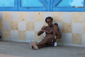 Cuban man with his son sitting outside their house